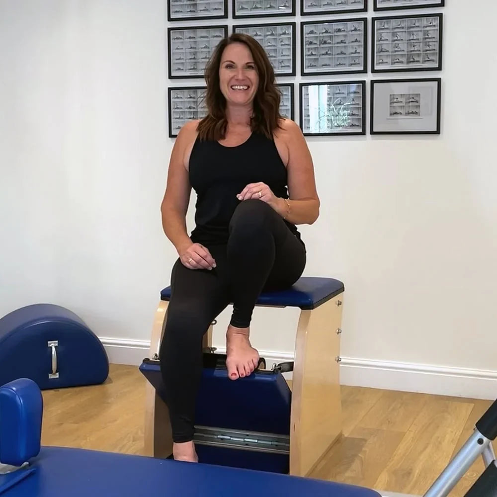 Pilates teacher sitting on a Pilates chair ready to teach a class