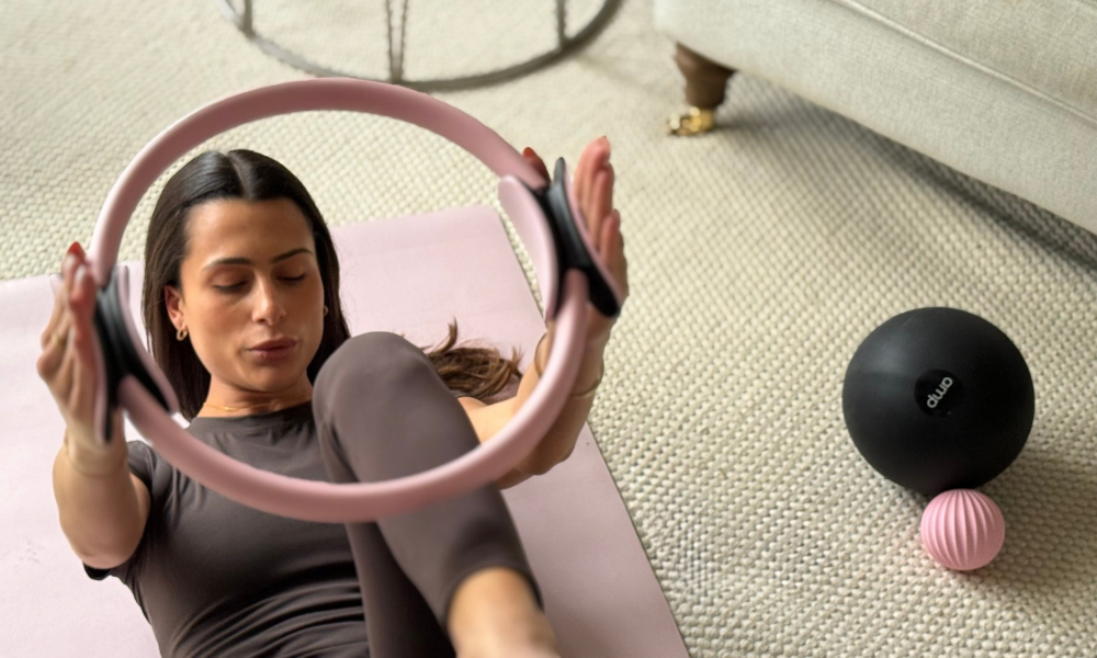 lady in her living room holding an amp Pilates ring completing a Pilates workout at home