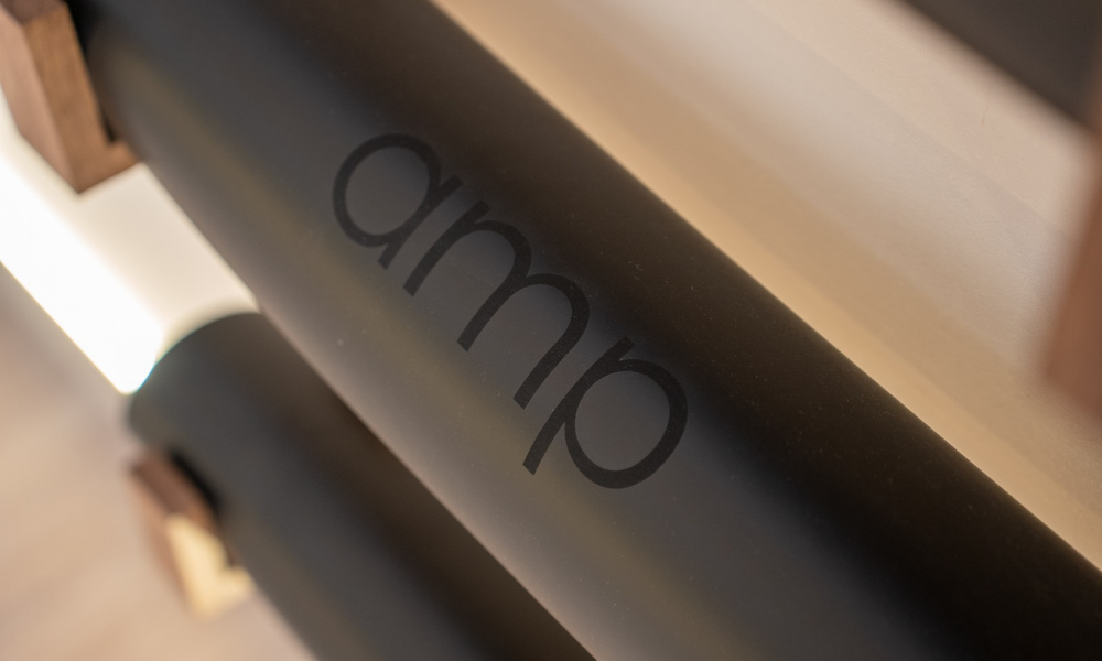 black yoga mat with amp logo rolled and stored on the wall