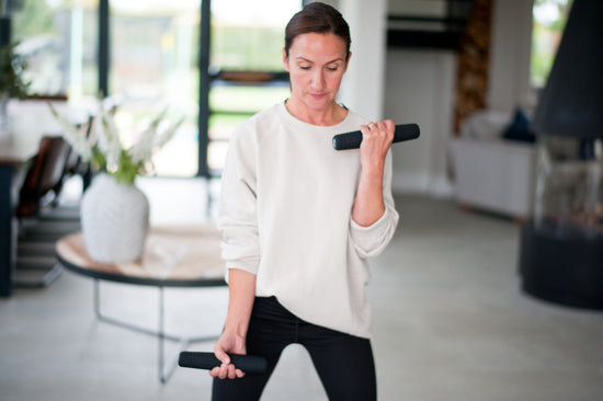 Lady with black pilates weights in home workout position