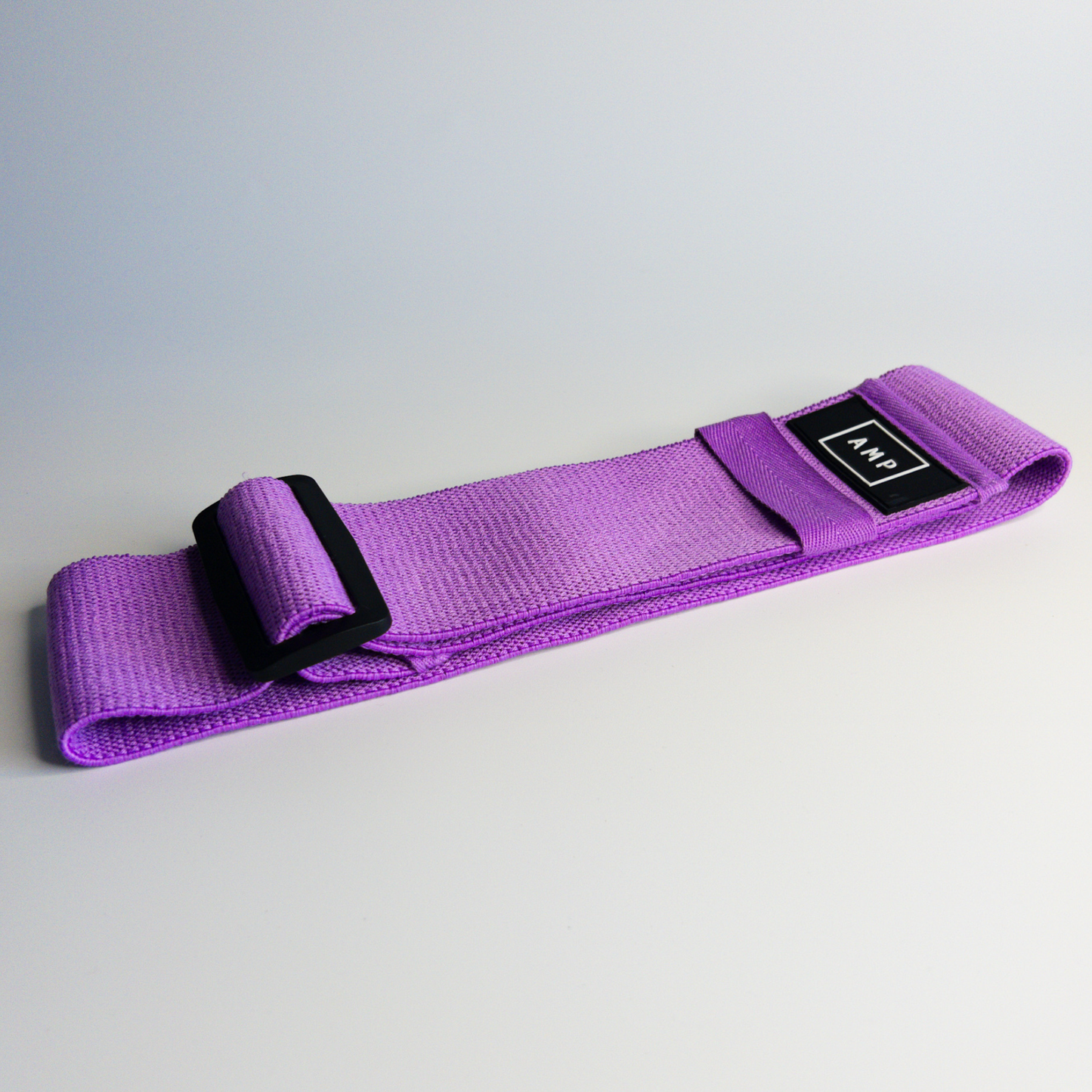 Purple resistance band with a black buckle on a light gray background