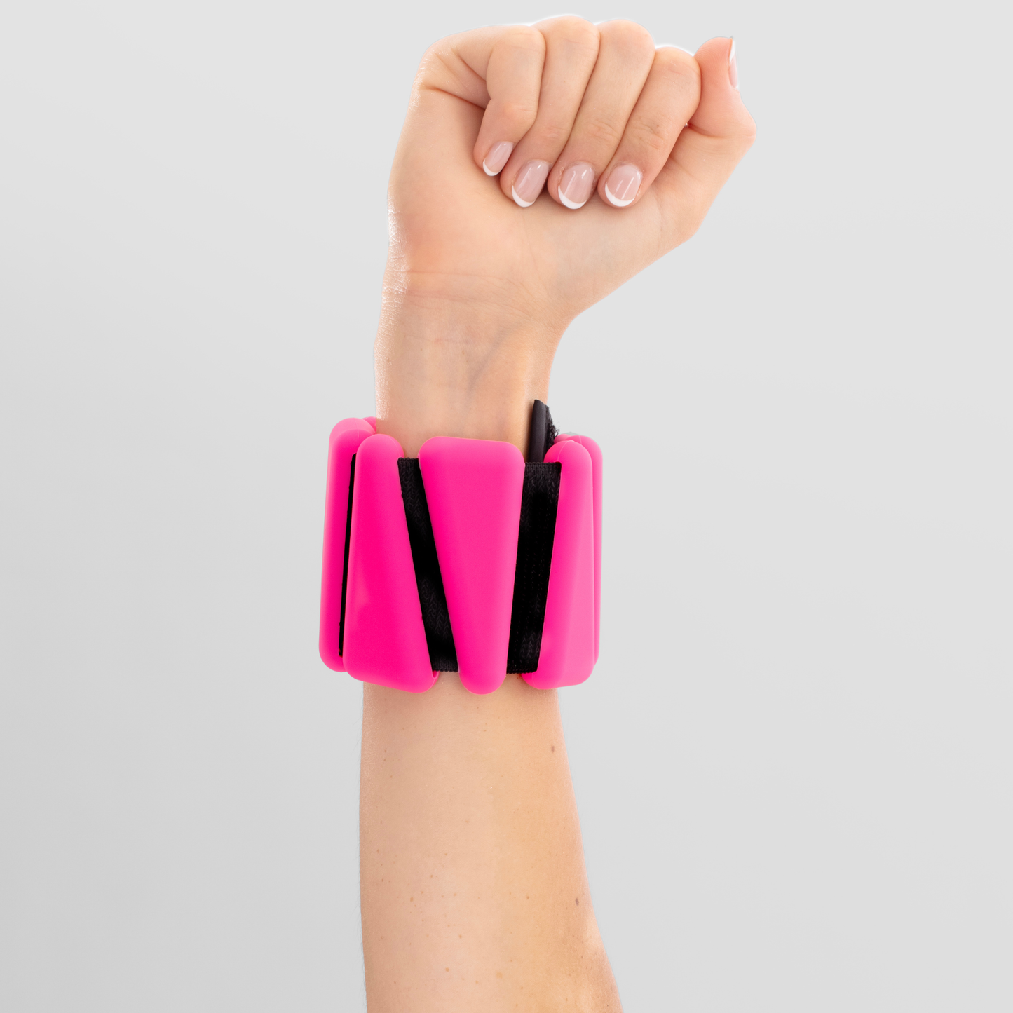 Pink wrist weight on a wrist against a gray background